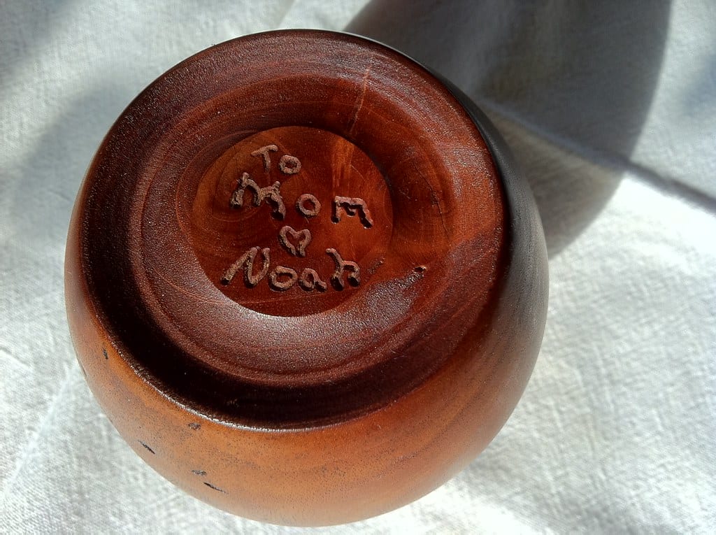 A small turned mahogany bud vase made from a weathered tree branch