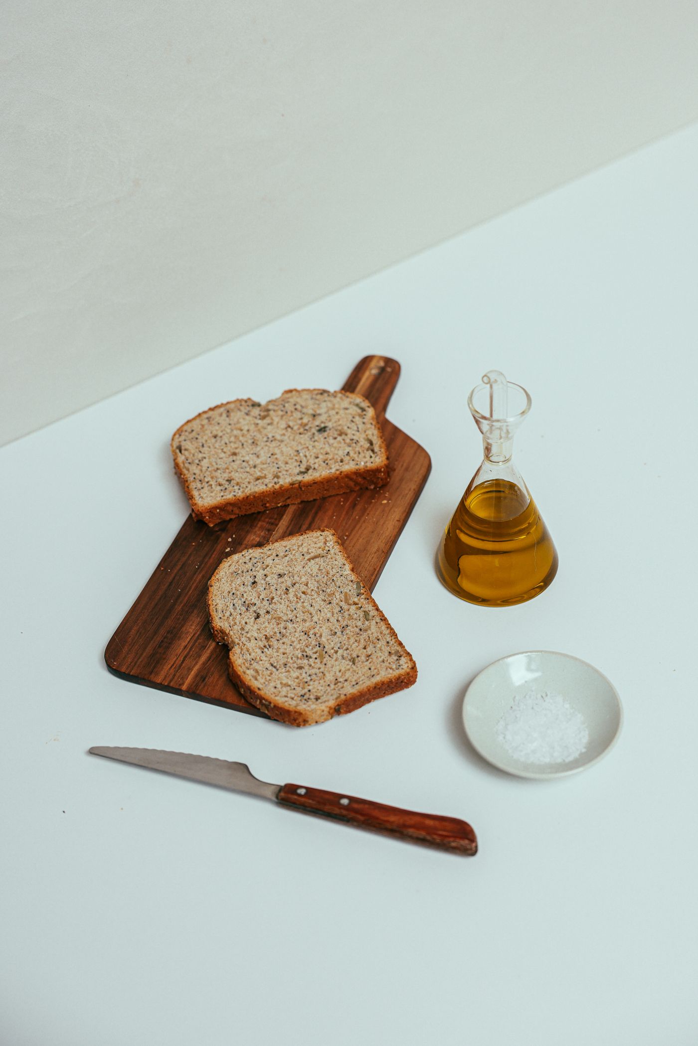 A wooden chopping board on a kitchen counter beside a bottle of oil