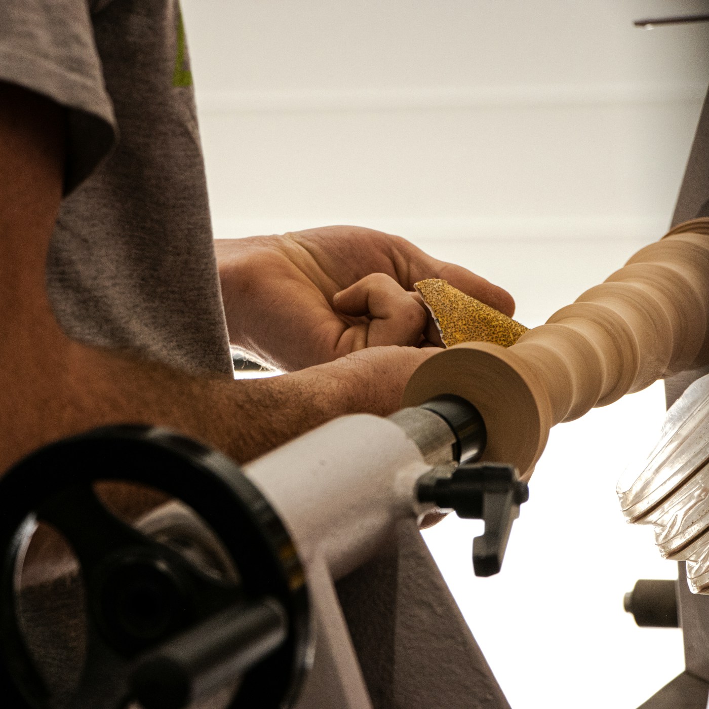 A clean woodturning workshop with dust collection visible under the lathe and the lathe and shop organized