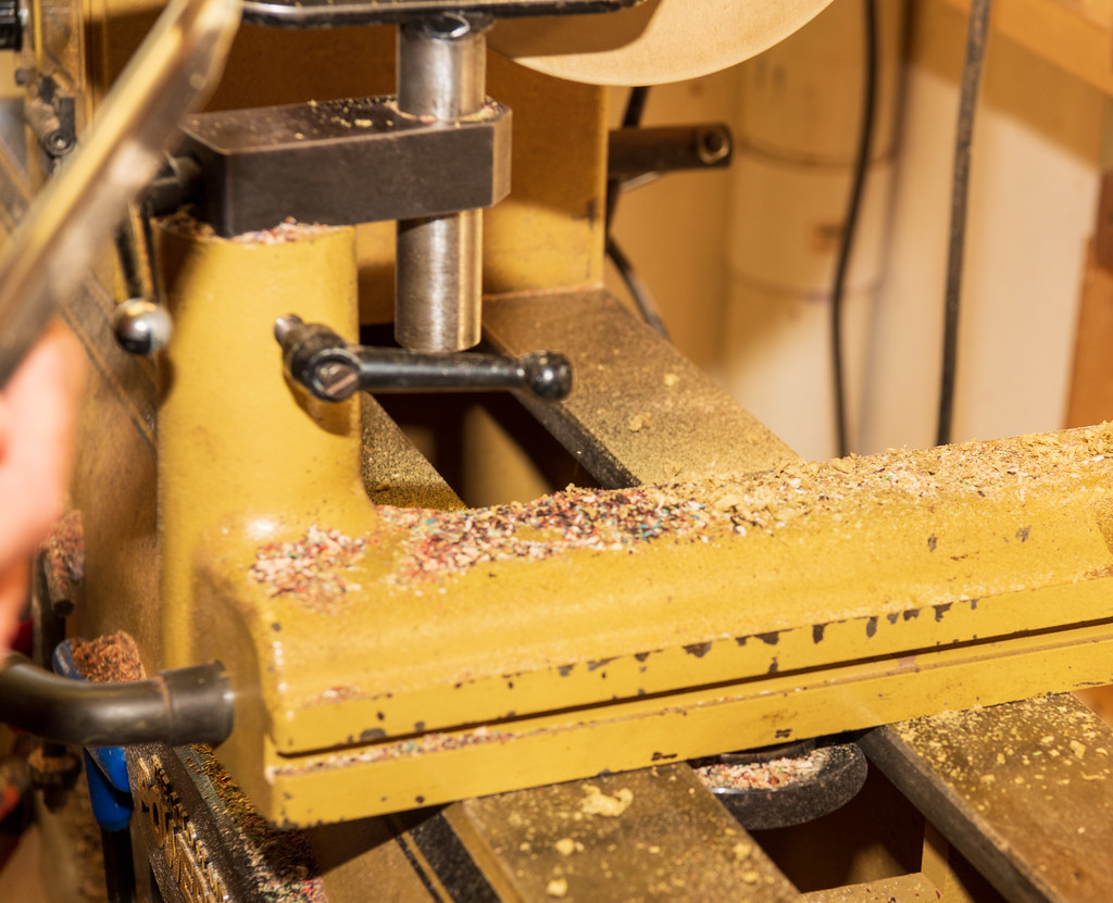 Wood shavings curl off a lathe during turning, the machine in motion