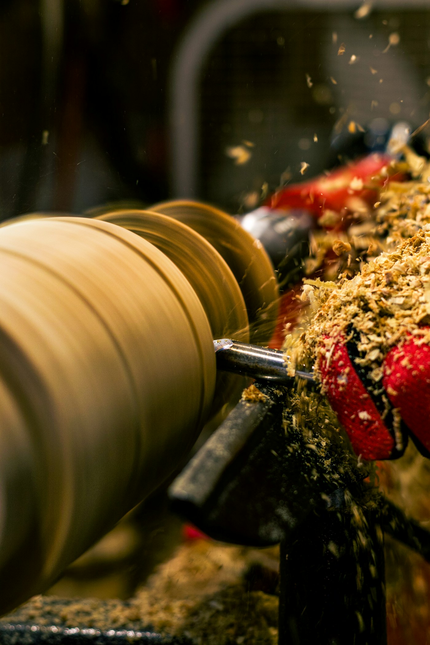 A woodworker shapes a large piece at a lathe in a professional workshop