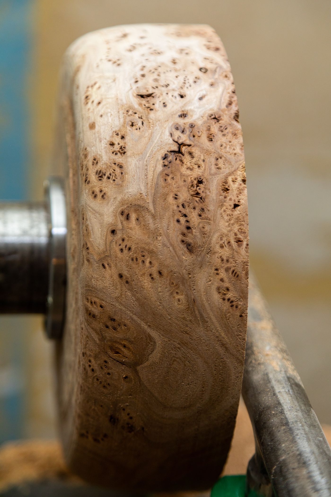 Close-up of a woodturner shaping a piece on a lathe with the wood grain visible