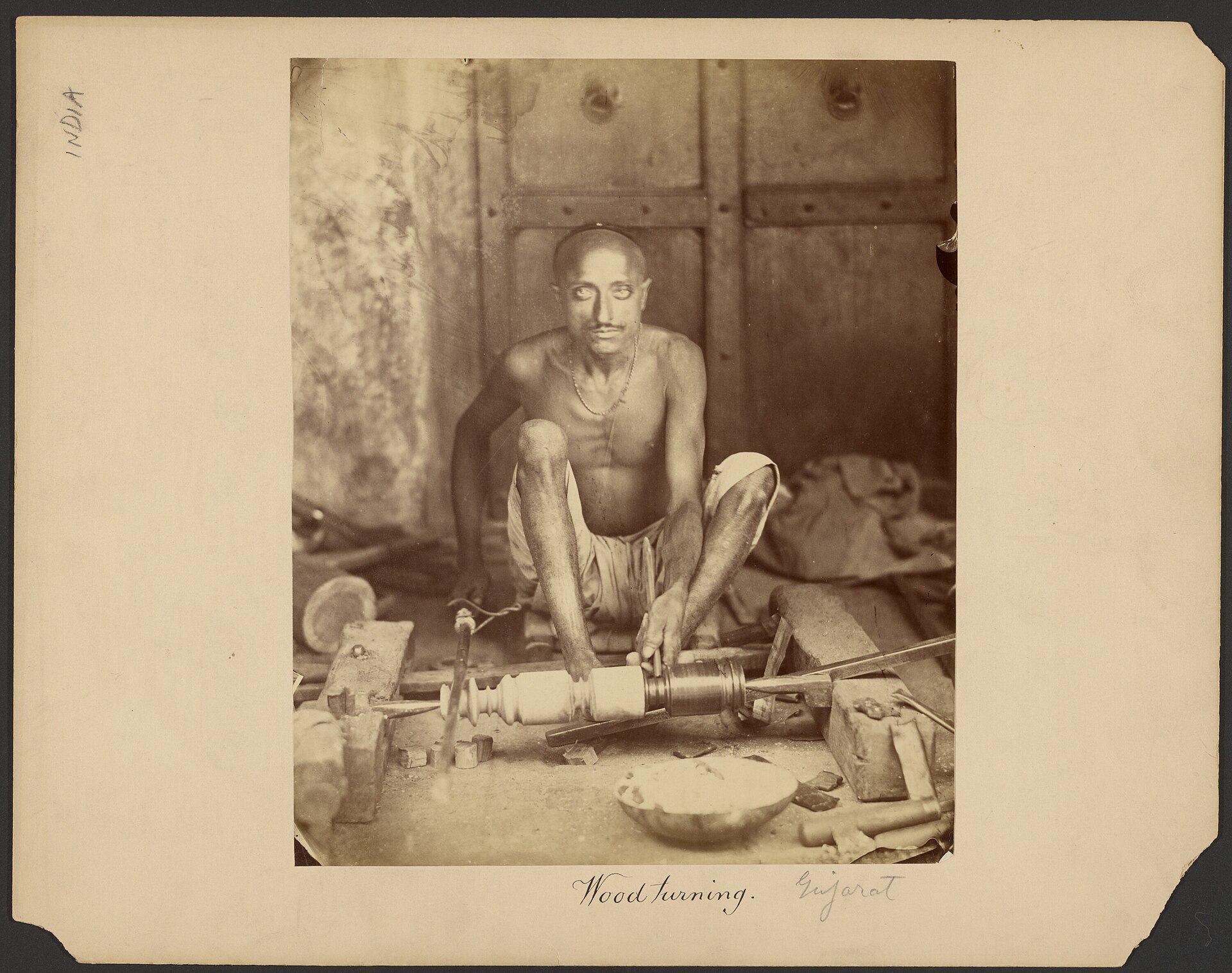 Traditional woodturner at a pole lathe in Gujarat, India, shaping a wooden piece