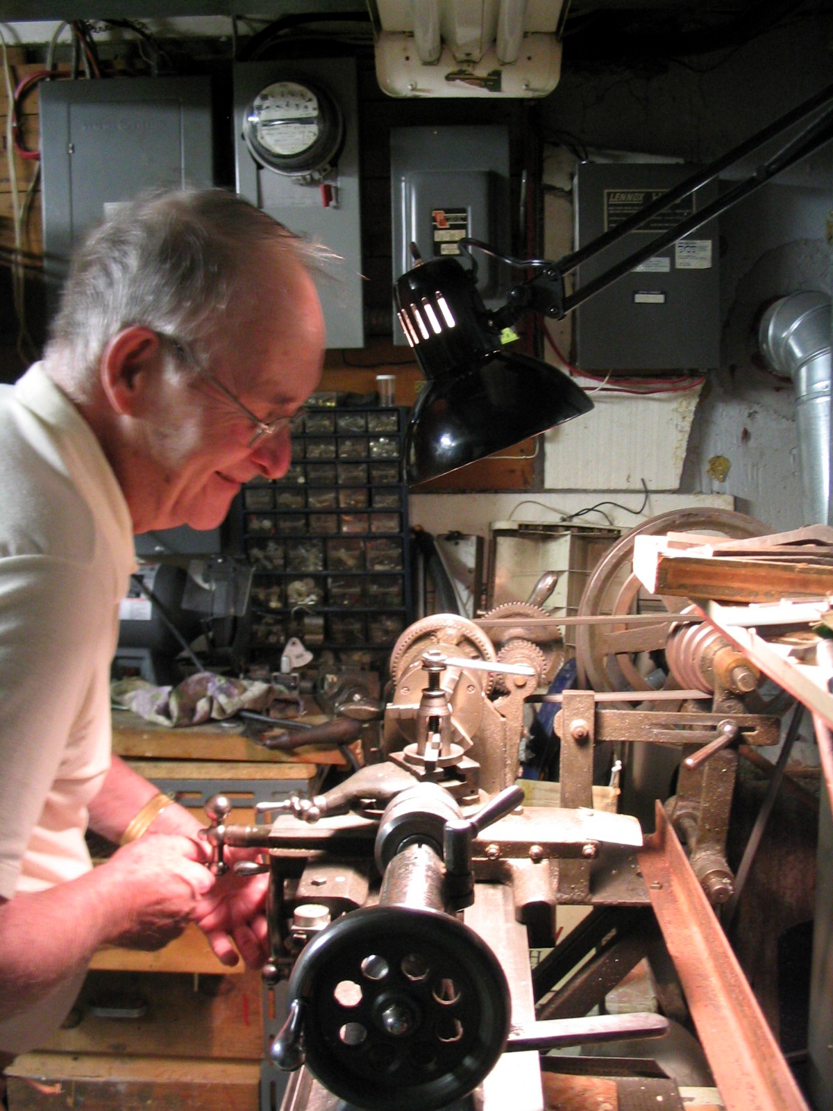 Lynn, a woodturner, at his old lathe in a workshop, shaping a piece with a gouge